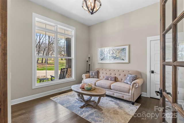 living room featuring an inviting chandelier, baseboards, and dark wood finished floors