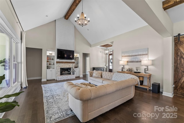 living area featuring beam ceiling, dark wood-type flooring, a barn door, and a chandelier