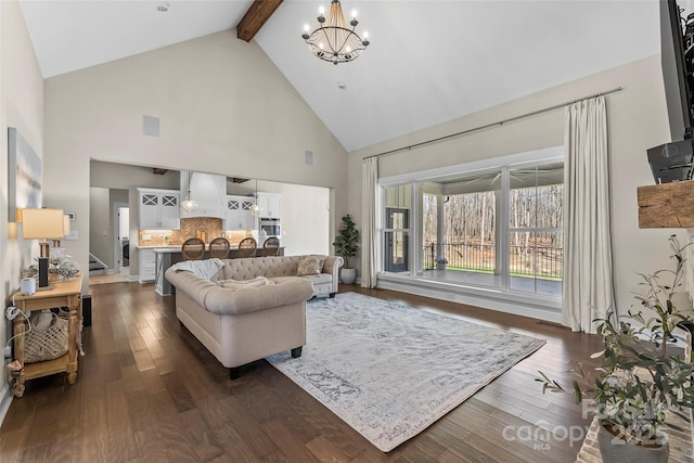 living area featuring high vaulted ceiling, visible vents, beamed ceiling, dark wood-style floors, and an inviting chandelier