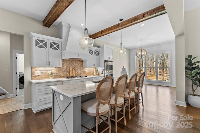 kitchen featuring a sink, light stone countertops, tasteful backsplash, custom exhaust hood, and stainless steel appliances