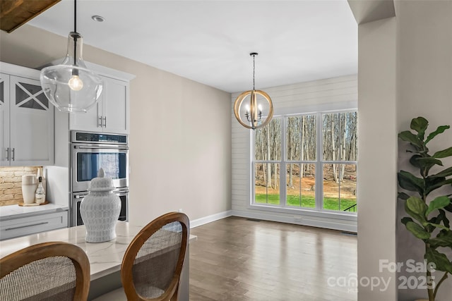 dining space with baseboards, visible vents, wood finished floors, and a notable chandelier