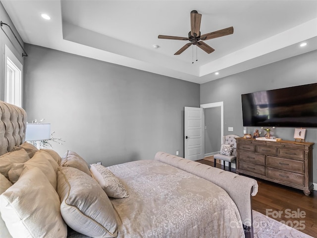 bedroom featuring a tray ceiling, wood finished floors, recessed lighting, and a ceiling fan