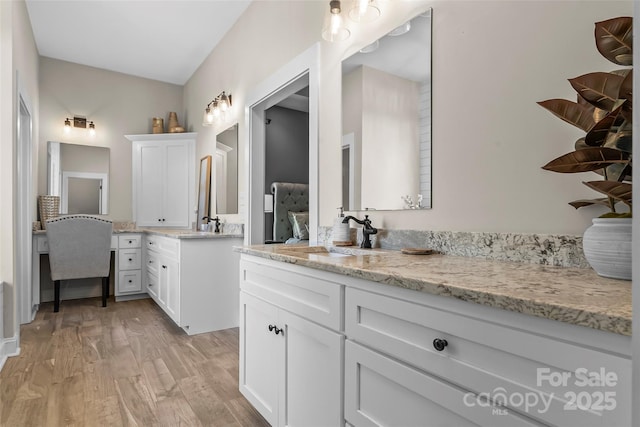 full bathroom featuring a sink, two vanities, and wood finished floors