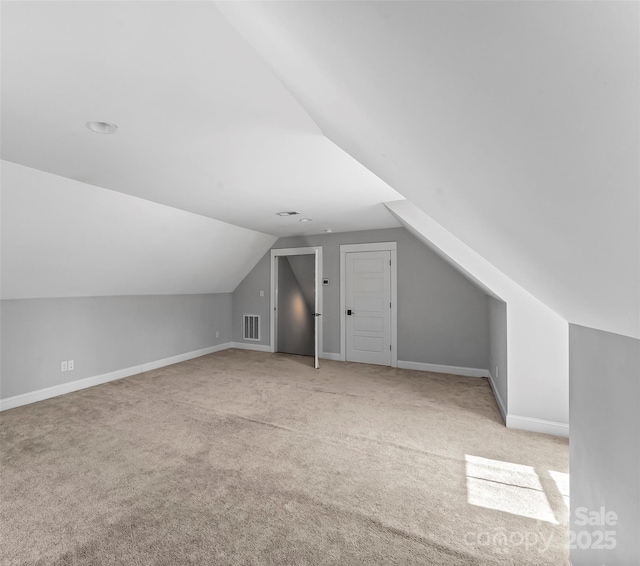 additional living space featuring baseboards, visible vents, lofted ceiling, and carpet
