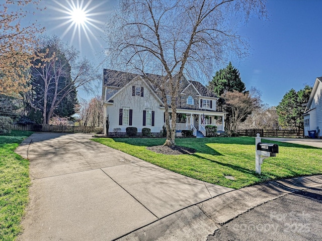 view of front of home with driveway, a front yard, a porch, and fence