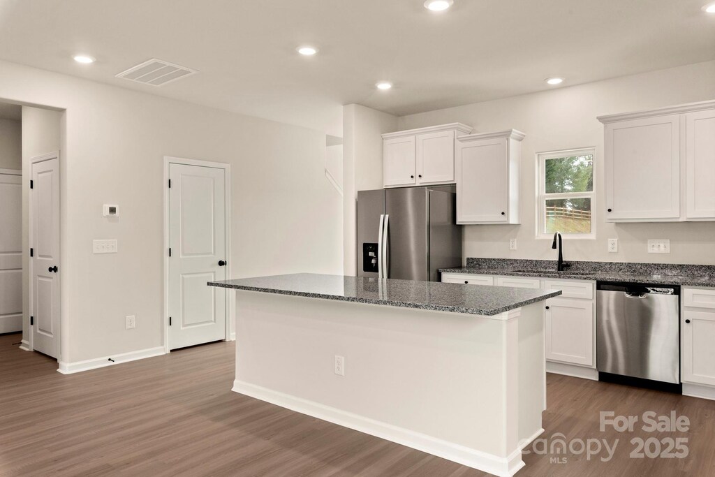 kitchen with visible vents, a kitchen island, a sink, appliances with stainless steel finishes, and white cabinetry