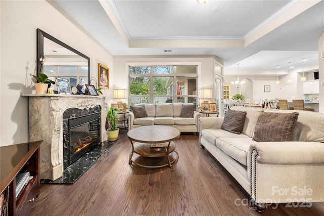 7909 Parknoll Dr, Huntersville, NC 28078 - living room with wood finished floors, a premium fireplace, a tray ceiling, crown molding, and a notable chandelier