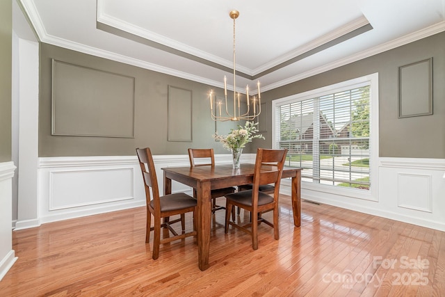 615 Vega St NW, Concord, NC 28027 - dining space featuring a decorative wall, light wood-style floors, a raised ceiling, a chandelier, and ornamental molding