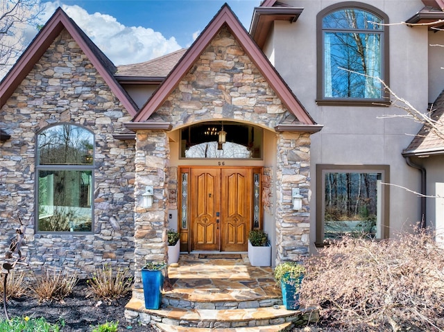 doorway to property featuring stucco siding and stone siding