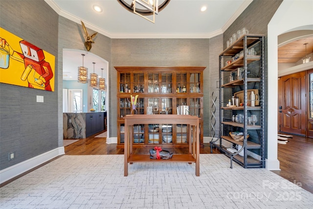 home office featuring baseboards, wood finished floors, arched walkways, and ornamental molding
