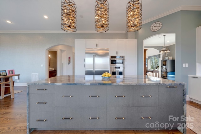 kitchen featuring gray cabinets, wood finished floors, arched walkways, and stainless steel appliances