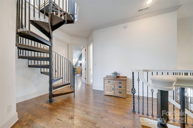 stairs featuring wood finished floors, ornamental molding, baseboards, and visible vents