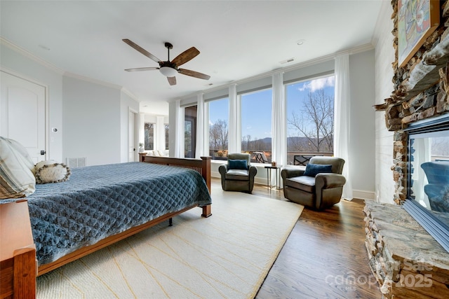 bedroom featuring visible vents, wood finished floors, ornamental molding, and a fireplace