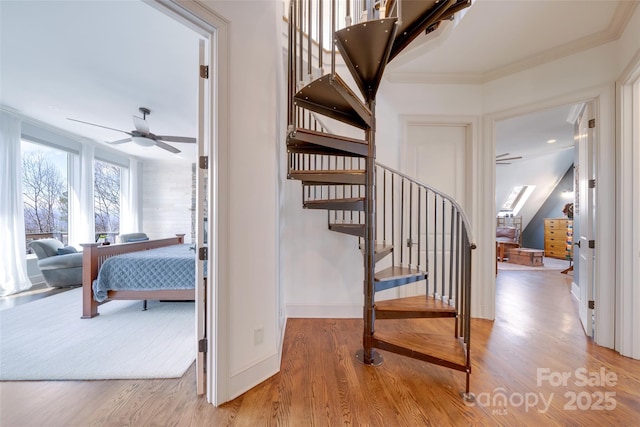staircase featuring baseboards, ceiling fan, wood finished floors, and crown molding