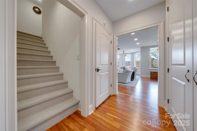 stairs with baseboards, wood finished floors, and recessed lighting