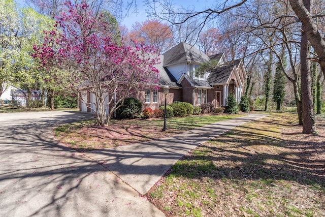view of front of house with a garage, brick siding, and driveway