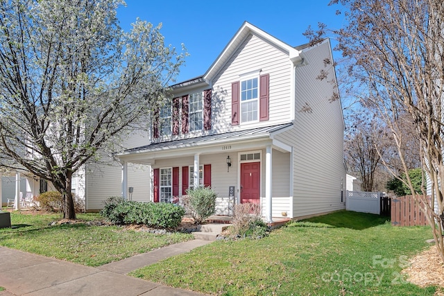 traditional home with a front lawn, a standing seam roof, a porch, fence, and metal roof
