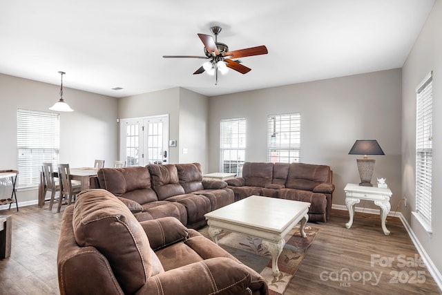 living area with a healthy amount of sunlight, baseboards, ceiling fan, and wood finished floors