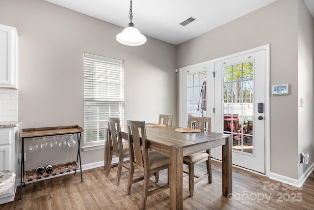 dining area featuring visible vents, baseboards, and wood finished floors