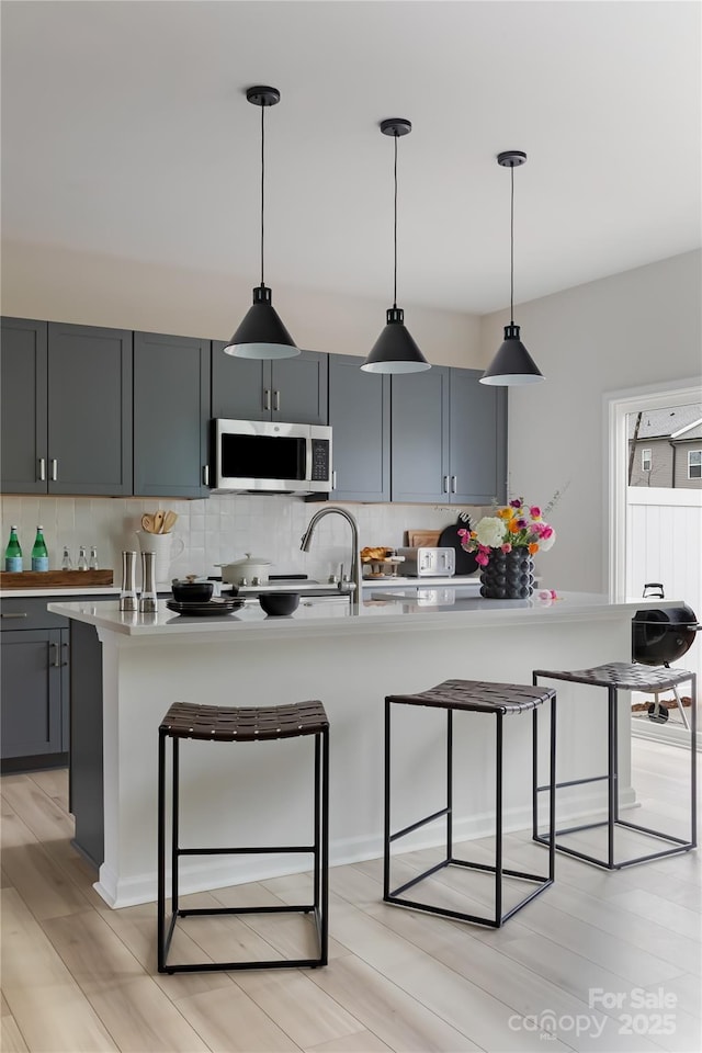 3012 Hutton Gardens Ln, Charlotte, NC 28269 - kitchen with a breakfast bar, stainless steel microwave, light countertops, and decorative backsplash