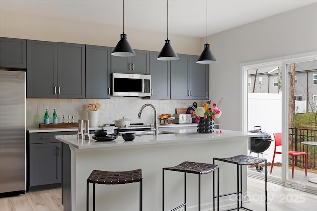3012 Hutton Gardens Ln, Charlotte, NC 28269 - kitchen with tasteful backsplash, decorative light fixtures, a breakfast bar area, light countertops, and appliances with stainless steel finishes