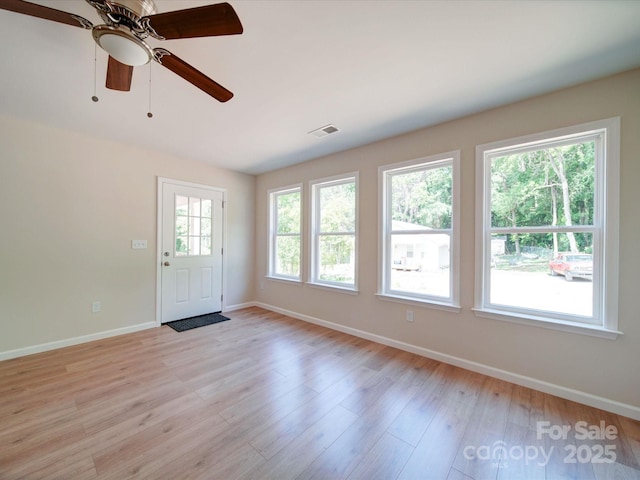 unfurnished room with a ceiling fan, light wood-style flooring, and baseboards