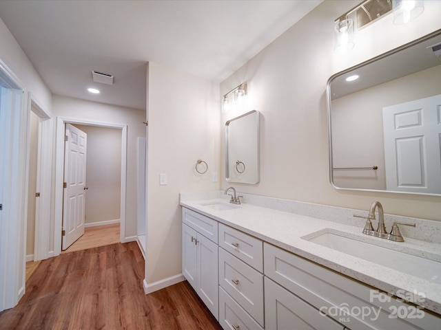 full bath with wood finished floors, baseboards, double vanity, and recessed lighting