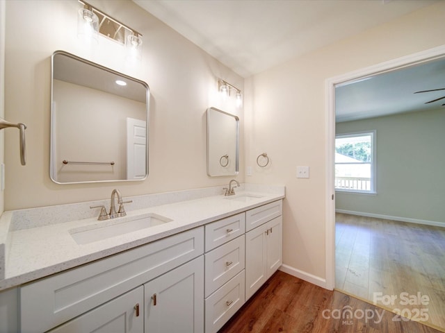 full bath featuring wood finished floors, baseboards, and double vanity
