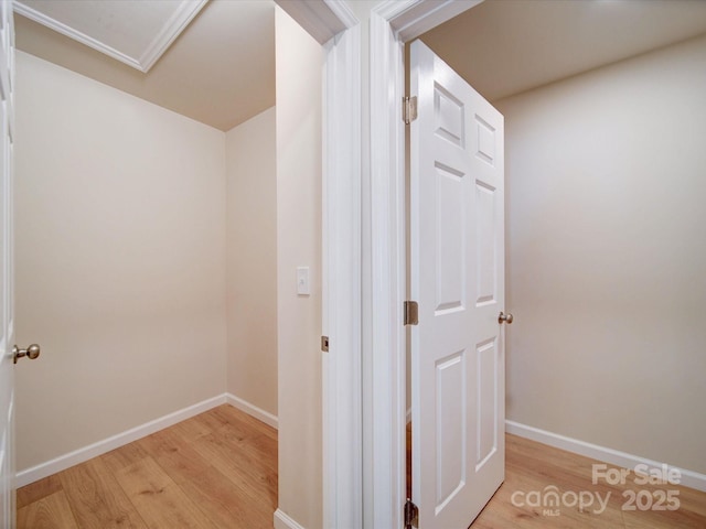 corridor featuring light wood-style flooring, baseboards, and attic access