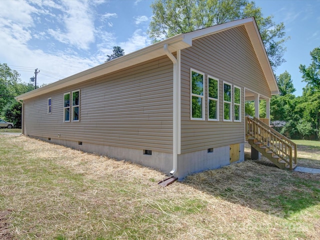 view of side of home with crawl space and stairs