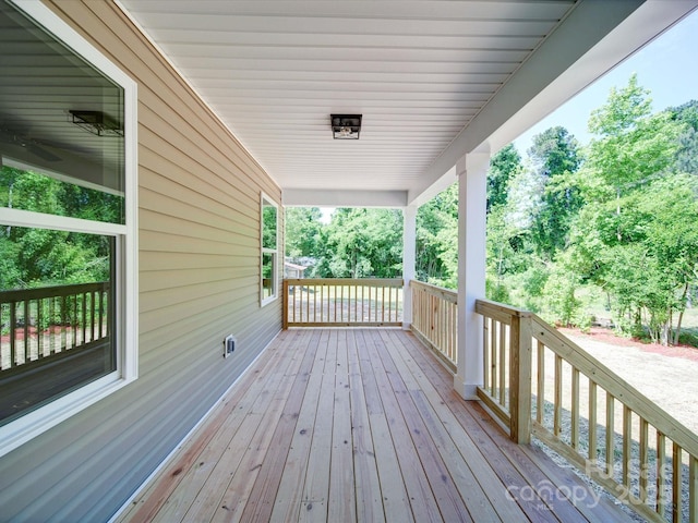 wooden deck with covered porch and view of scattered trees