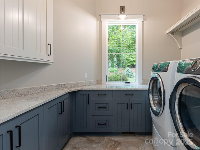 laundry area with cabinet space, a wealth of natural light, and washer and clothes dryer