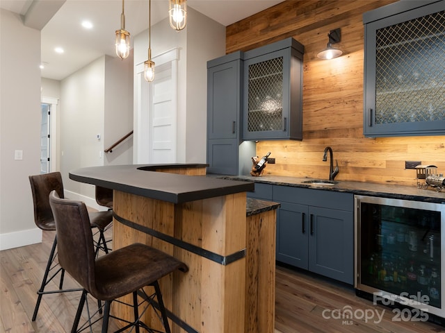 bar featuring a sink, wine cooler, backsplash, and dark wood finished floors