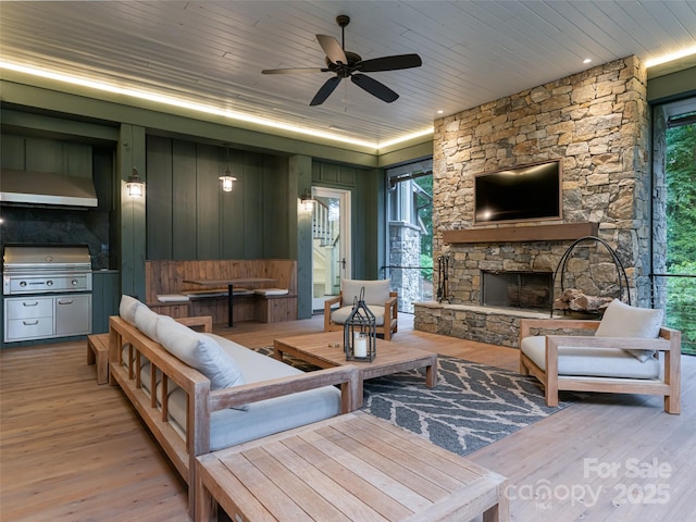 living room featuring a stone fireplace, wood ceiling, a ceiling fan, and wood finished floors