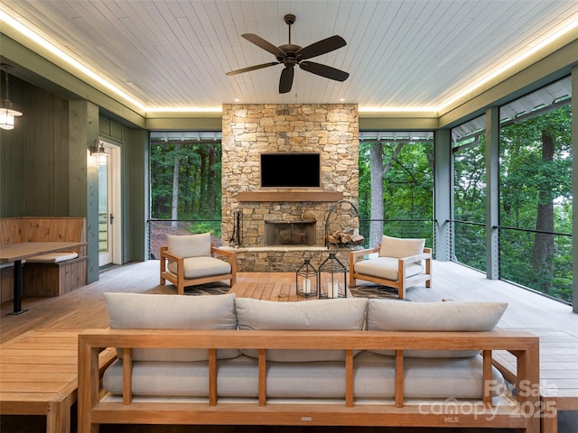 interior space with an outdoor living space with a fireplace and ceiling fan