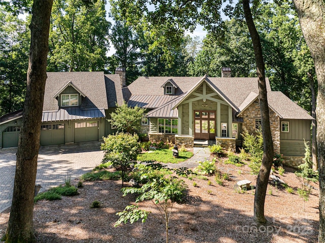 view of front facade featuring board and batten siding, a shingled roof, french doors, stone siding, and driveway