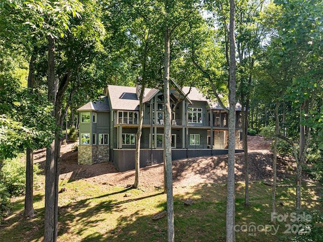 rear view of house with stone siding and a shingled roof