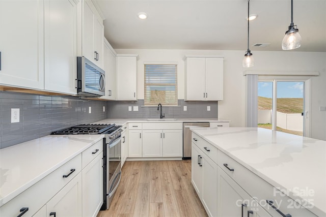 kitchen featuring plenty of natural light, light wood-style flooring, white cabinets, stainless steel appliances, and a sink