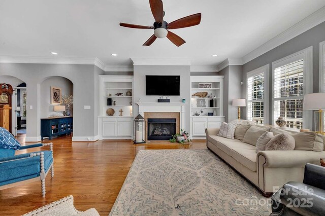 4536 Rustling Woods Dr, Denver, NC 28037 - living area featuring ceiling fan, wood finished floors, arched walkways, a fireplace, and ornamental molding