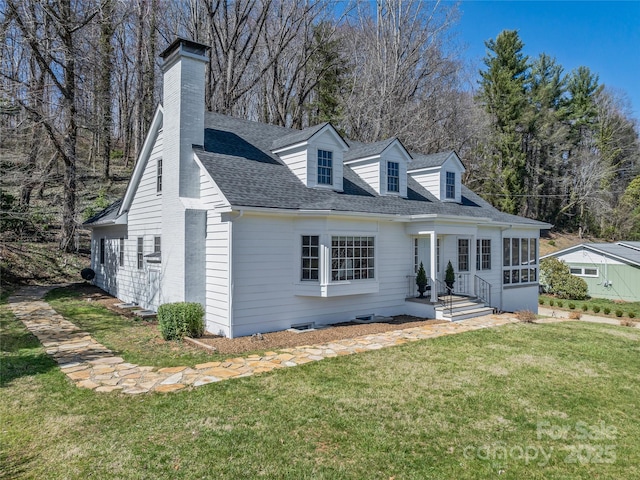 cape cod-style house with a chimney, a shingled roof, and a front yard