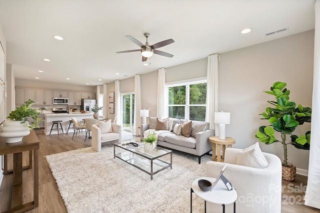 living area with light wood-type flooring, a ceiling fan, visible vents, and recessed lighting