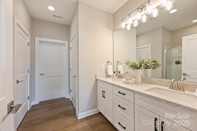 full bath with wood finished floors, a sink, baseboards, visible vents, and a stall shower
