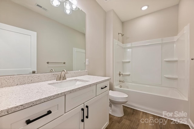 bathroom featuring wood finished floors, vanity, toilet, visible vents, and bathing tub / shower combination