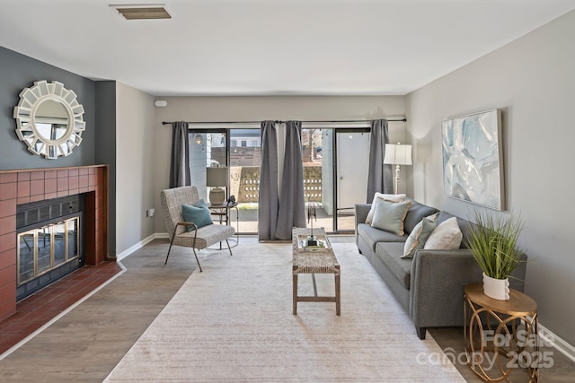 419 W 8th St, Charlotte, NC 28202 - living room with visible vents, baseboards, wood finished floors, and a tiled fireplace
