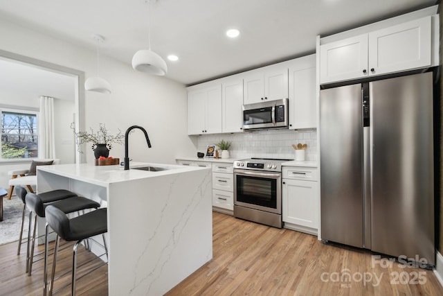 1749 Archdale Dr, Charlotte, NC 28210 - kitchen featuring appliances with stainless steel finishes, backsplash, white cabinetry, a breakfast bar, and decorative light fixtures