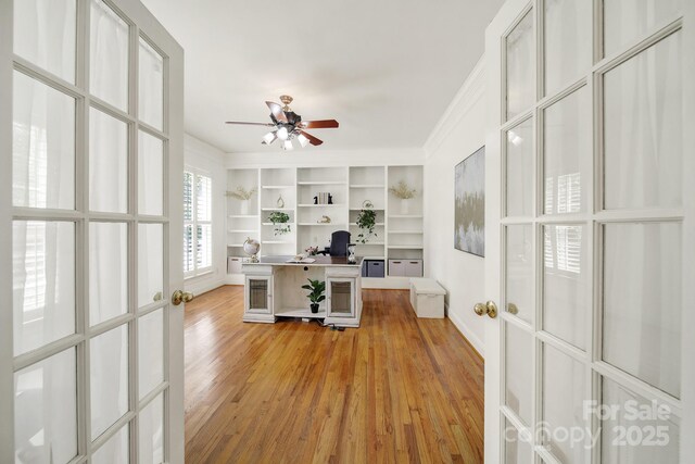 office with built in study area, baseboards, a ceiling fan, and light wood-style flooring