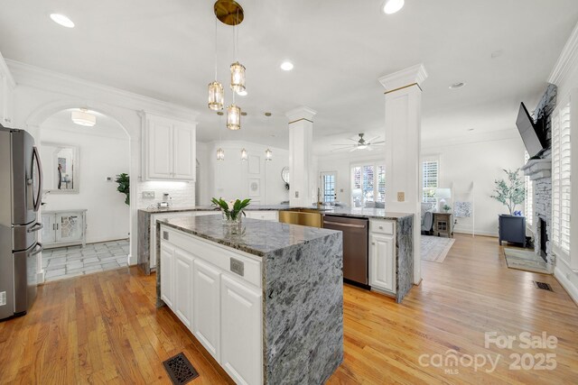 kitchen featuring a kitchen island, a fireplace, ornate columns, white cabinets, and stainless steel appliances