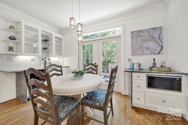 dining area featuring crown molding, baseboards, french doors, and light wood-type flooring