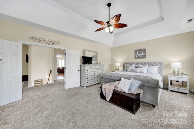bedroom featuring crown molding, baseboards, light colored carpet, a tray ceiling, and a ceiling fan