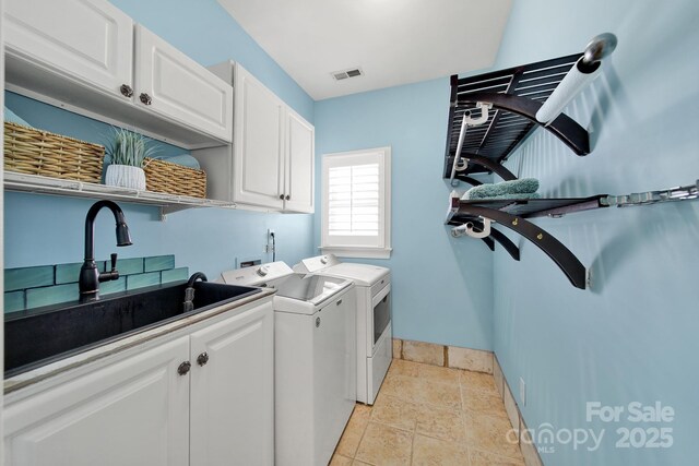 laundry room featuring visible vents, stone tile floors, washer and dryer, a sink, and cabinet space